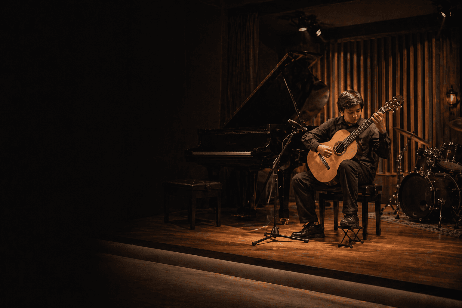 Estudiante tocando guitarra en un escenario íntimo de academia musical